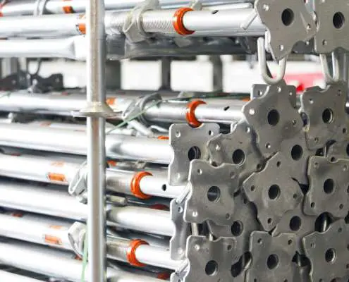 End-on view of a tight stack of galvanised steel adjustable shoring props stored in a yard.