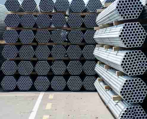 End on view of tightly stacked circular galvanised steel scaffolding tubes organized in bulk bundles.